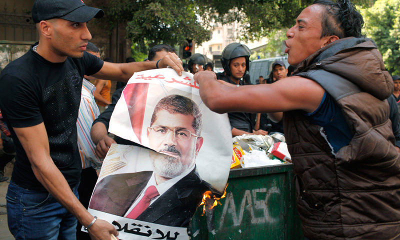 Local residents burn a poster of ousted President Morsi, which was taken after his supporters fled.
