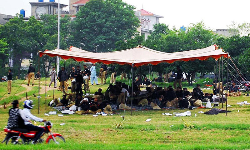 Police personnel sit on the grass near Faizabad to avert any untoward incident. -Online photo