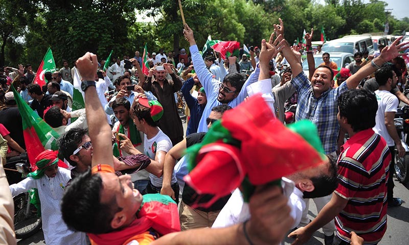 PTI supporters cheer as they gather outside the residence of Imran at the start of their protest march against government in Lahore on August 14, 2014. — Photo by AFP