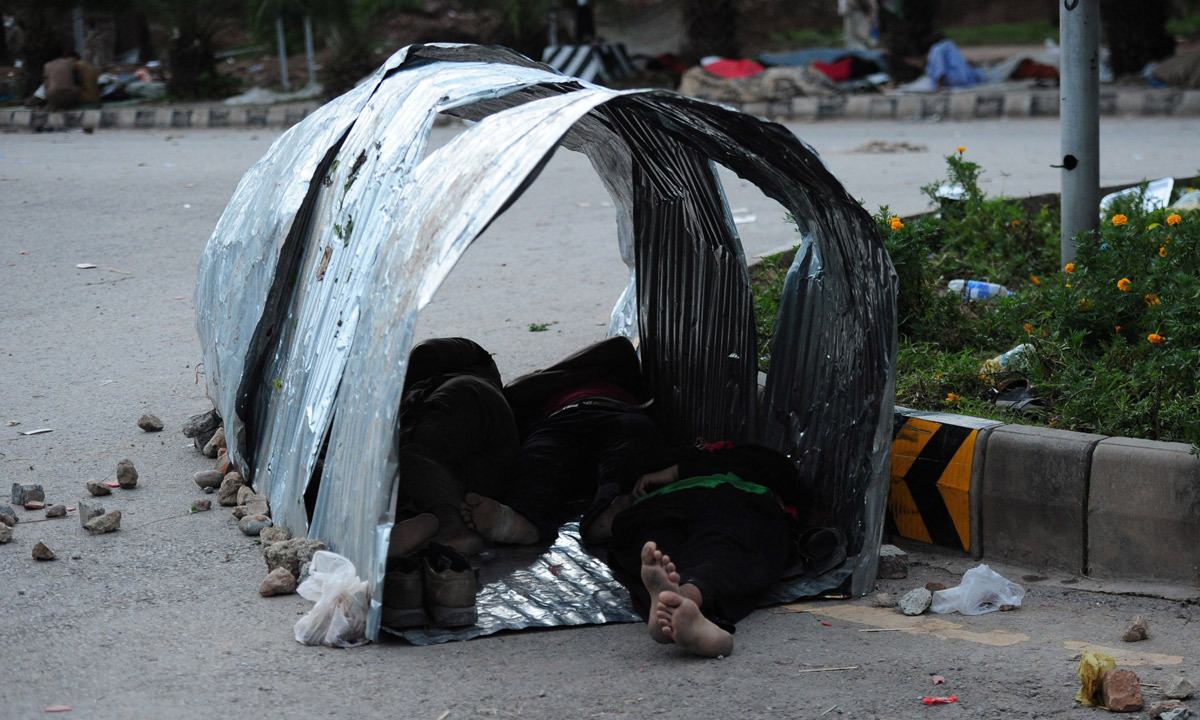 Supporters of Imran Khan and Tahirul Qadri rest during an anti-government protest in front of the parliament building in Islamabad. - Photo by AFP