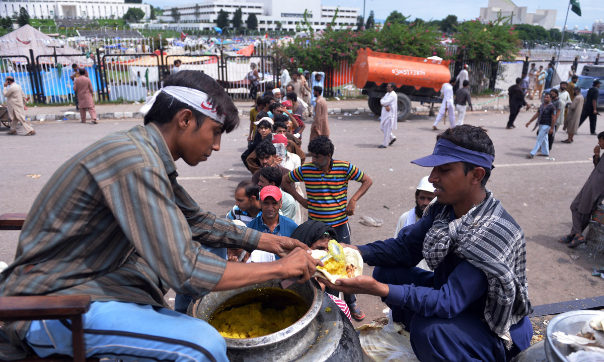 Supporters of Tahirul Qadri distribute food to supporters of Imran Khan in front of the parliament building in Islamabad. - Photo by AFP