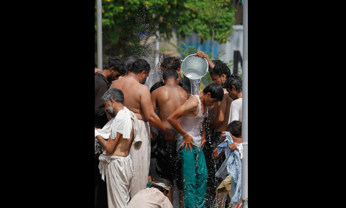 Protesters bathe at a leaking water supply line close to the parliament building where they are camped in Islamabad. - Photo by AP