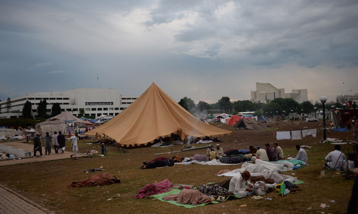 Supporters of Imran Khan and Tahirul Qadri rest during an anti-government protest in front of the parliament building in Islamabad. - Photo by AFP