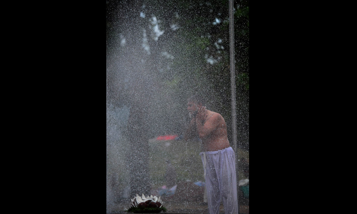 A protestor bathes at the roadside during an anti-government protest near the parliament building in Islamabad. - Photo by AFP
