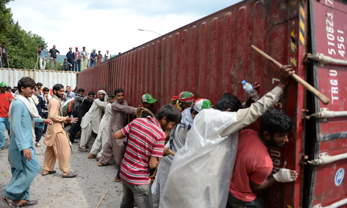 Supporters of Imran Khan and Tahirul Qadri remove a container during an anti-government protest near the parliament building in Islamabad. - Photo by AFP