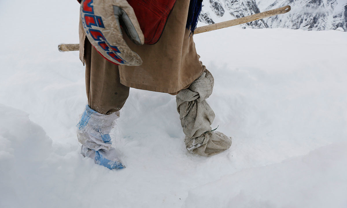 A porter leaves snow-covered Concordia, the confluence of the Baltoro and Godwin-Austen glaciers, wearing make shift gaiters near K2 in the Karakoram mountain range in Pakistan. -Reuters Photo