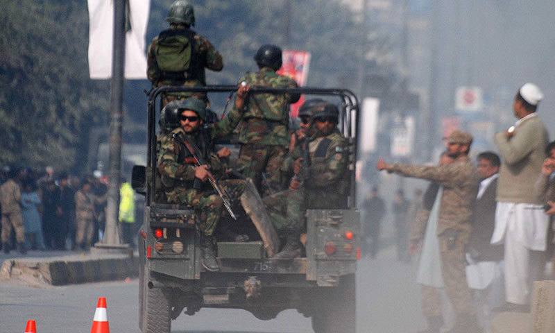 Security forces drive on a road leading to the Army Public School that is under attack by Taliban gunmen in Peshawar - Reuters