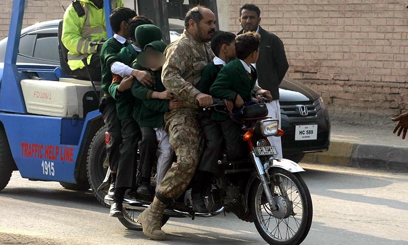 Army personnel shifting the school children on motorbike following the attack on Army Public School situated on Warsak Road. — INP