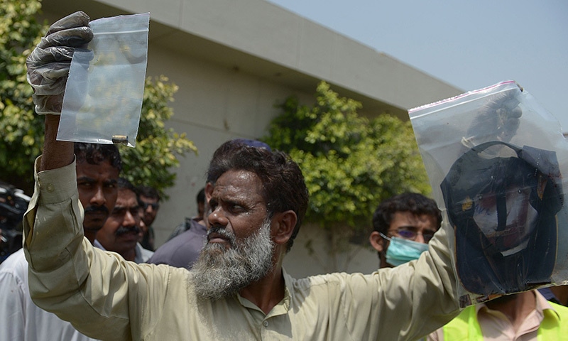 A plain-clothes police official holds up evidence collected from the scene of an attack by gunmen on a bus carrying Ismailis in Karachi on May 13, 2015.— AFP