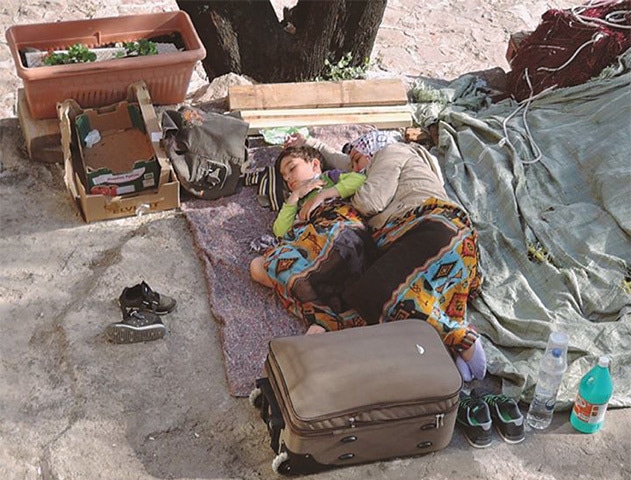 Exhausted and tired, refugees sleep with whatever little belongings they have
