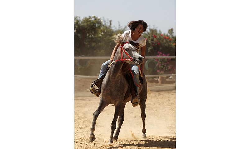 Raja Kheir rides a stray horse ─ AFP