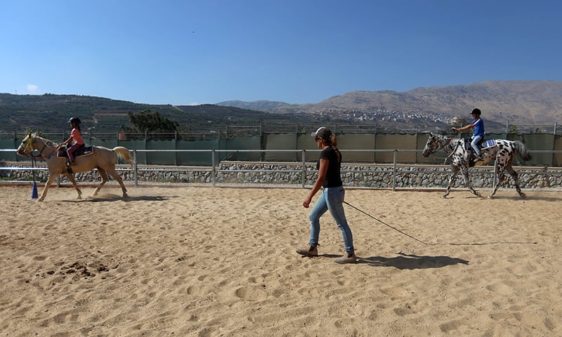Raja supervises kids during their riding lesson ─ AFP