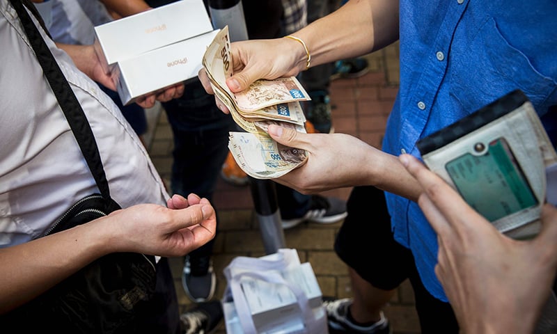 Parallel traders buy and sell the new iPhone 7 during the opening day of sales outside an Apple store in Hong Kong.— AFP