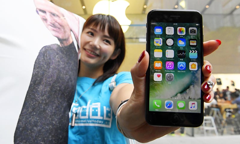 A woman poses with Apple's iPhone 7 after purchase at an Apple store in Tokyo.— AP