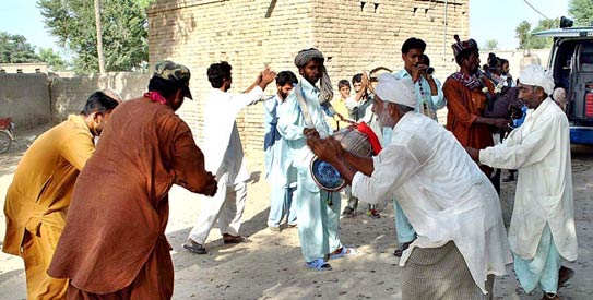 Members of Azhar Hussain’s family celebrate his gold medal win at the Commonwealth Games in front of his house in Muzzaffargarh. —APP Photo