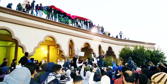 Libyan protesters hold a giant flag on top of a building during a demonstration in the seaport city of Tobruk