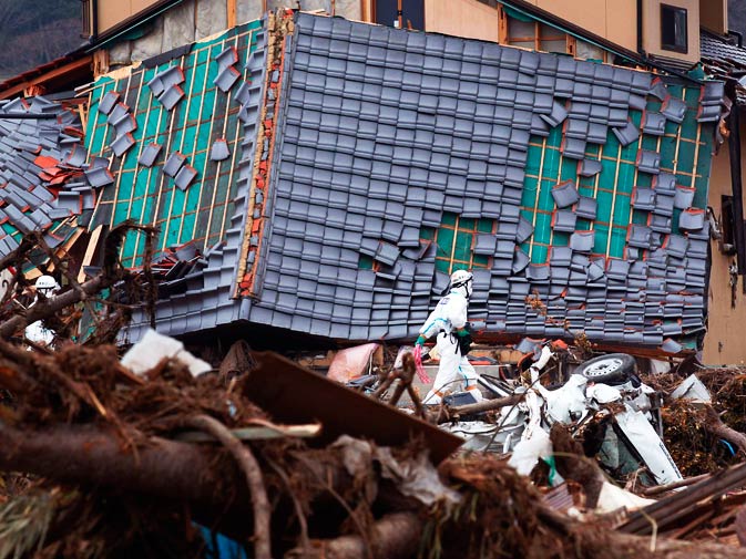 A police officer walks past a damaged house while searching for bodies. – Photo by Reuters