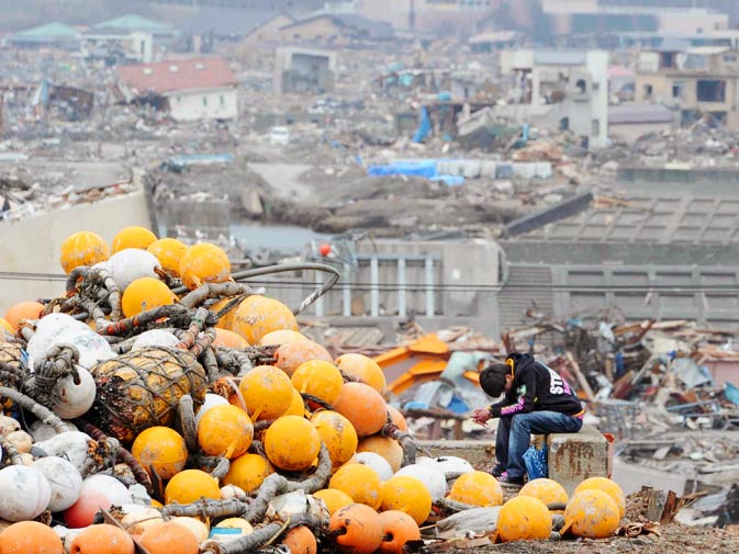 A teenager sits among the rubble of his aunt's residence. – Photo by AP