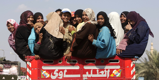 Girls look back as they sit on a vehicle in Cairo