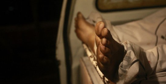 The feet of a man, who was killed in a shootout with police, are seen from an ambulance outside a Karachi hospital