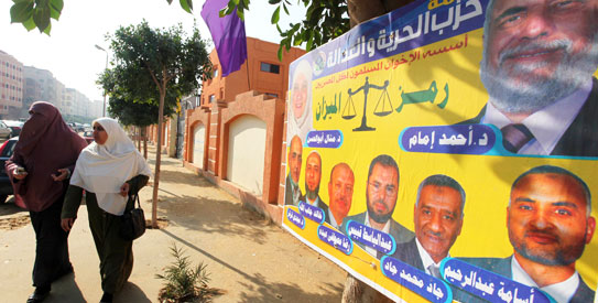 Women walk beside an election poster by Egypt's Muslim Brotherhood "The Freedom and Justice Party'" outside a polling station in Cairo —Reuters photo
