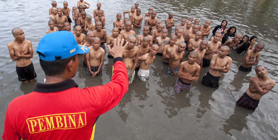 A police officer gives instruction to a group of detained Indonesian punks in a lake after their hair was shaved off at a police school in Aceh Besar in Aceh province. —AFP Photo