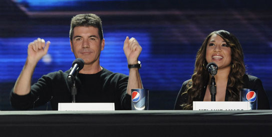 Simon Cowell reacts with Amaro during a news conference for the television show "The X Factor" held in Los Angeles