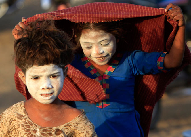 Pakistani scavenger children paint their faces with talcum powder that they found in the garbage in Karachi, Pakistan on Monday, March 12, 2012. ?
 AP Photo