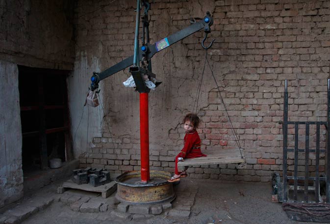 A girl sits on a weighing scale at a wood saw mill in Lahore March 9, 2012. ?
Reuters Photo