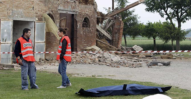 Carabinieri paramilitary police officers stand beside the body of a woman after an earthquake in Sant' Agostino near Ferrara May 20, 2012. A strong earthquake rocked a large swathe of northern Italy early on Sunday morning, causing at least three deaths and collapsing rural factories and ancient bell towers in towns.  REUTERS/Giorgio Benvenuti  ( ITALY - Tags: DISASTER ENVIRONMENT)