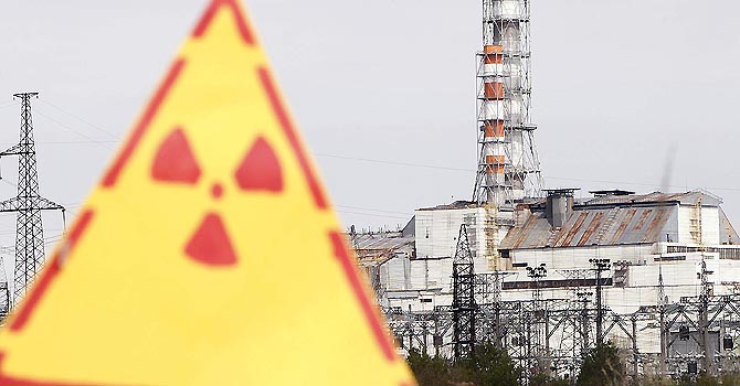 Hazard sign indicating radiation is seen in front of a containment shelter for the damaged fourth reactor at the Chernobyl nuclear power plant