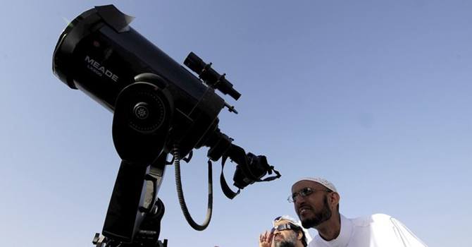 Men use a telescope and eclipse shades to watch the planet Venus transiting across the sun. –Reuters