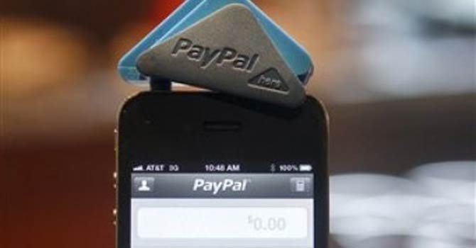A PayPal employee holds a smartphone with a PayPal Here card reader attached, in San Francisco, California. – AP 