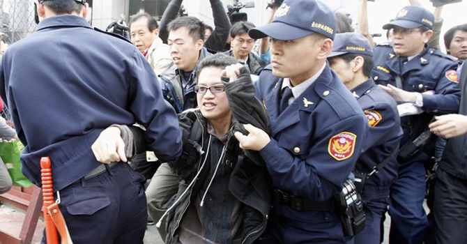 Police officers take an activist away as he protests against the Taiwan government's plan to allow beef imports from the United States in front of the American Institute in Taiwan (AIT), the de facto U.S. embassy in Taipei. – Reuters 