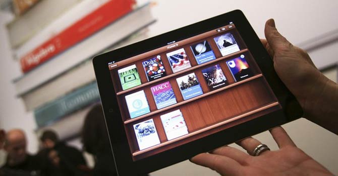 A woman holds up an iPad with the iTunes U app. – Reuters 