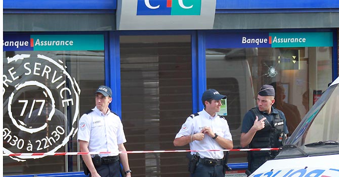 Police officers take position in front the CIC bank in the southern French city of Toulouse, Wednesday, June 20, 2012. A gunman who authorities say had past psychiatric problems took four people hostage Wednesday in a bank in the southern French city of Toulouse, claiming he was acting for religious reasons.Background right a bullet hole. (AP Photo/Bob Edme)