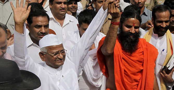 India's anti-corruption crusader Anna Hazare, left, and Indian yoga guru Baba Ramdev hold hands as they greet their supporters after paying their tributes at Rajgaht, Mahatma Gandhi memorial, in New Delhi, India, Sunday, June 3, 2012. India's iconic anti-corruption campaigners Hazare and Ramdev are holding a daylong fast near Indian parliament house to press the government to act against widespread graft and bring back hundreds of billions of dollars stashed overseas. (AP Photo/Manish Swarup)