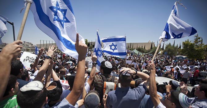 Jewish settlers wave Israeli flags during a protest against the proposed decision to evacuate a West Bank outpost in the Ulpana neighborhood, in the West Bank settlement of Beit El near the Palestinians city of Ramallah, outside the Supreme Court, in Jerusalem, Wednesday, June 6, 2012. Israel's parliament on Wednesday paved the way for the demolition of an illegal West Bank outpost by rejecting an attempt by hardline lawmakers to prevent the move. The development sets the stage for a showdown between Prime Minister Benjamin Netanyahu and Jewish settlers and their supporters in his government. Israel's Supreme Court has said the Ulpana outpost is illegal because it was built on private Palestinian land and ordered the outpost's five buildings taken down by July 1, a ruling Netanyahu says he will respect. (AP Photo/Oded Balilty)