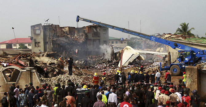 People watch as a crane removes wreckage from the site of a plane crash at Iju-Ishaga neighbourhood, Lagos June 4, 2012. Nigeria recovered bodies and searched for clues on Monday after an airliner crashed in a residential area of Lagos overnight, killing all 153 people on board and prompting the president to declare three days of mourning. REUTERS/Akintunde Akinleye (NIGERIA - Tags: DISASTER)
