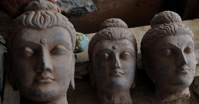 A man arranges seized ancient statues in a police station in Karachi.—AFP Photo