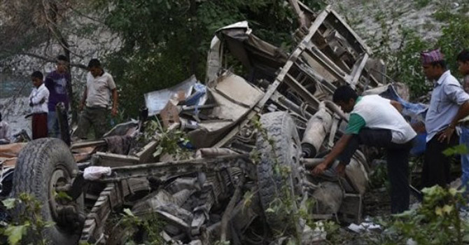 Nepalese villagers look at the remains of a bus that veered off a mountain.—AP Photo