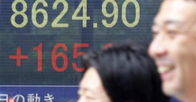 People walk by an electronic stock board of a securities firm. — AP Photo
