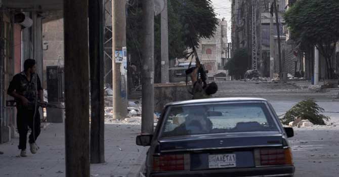Fighters take to the streets in the Salaheddin district of the restive Syrian city of Aleppo on July 29, 2012.  Syrian forces and rebels clashed violently in and around Aleppo before dawn as the battle for control of the northern city raged into a third day, with both sides claiming advances.  AFP PHOTO / PIERRE TORRES