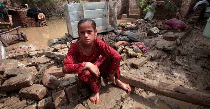 A girl sits on fallen part of her house due to heavy raining in Nowshera, near Peshawar. — AP Photo