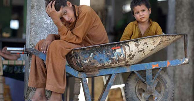 Pakistani boys sitting in a wheelbarrow wait for customers at a food market in Islamabad. — AFP Photo