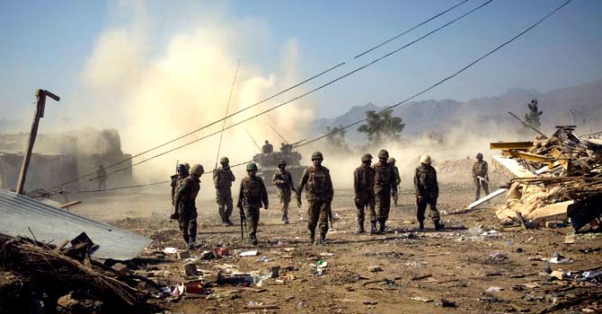 Army soldiers walk past damaged houses in Loi Sam, in the Bajur tribal region in 2008. – File photo by AP