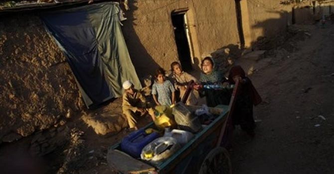 Pakistani girls push a cart loaded with jerrycans filled with water in an alley of a poor neighbourhood on the outskirts of Islamabad. — AP Photo