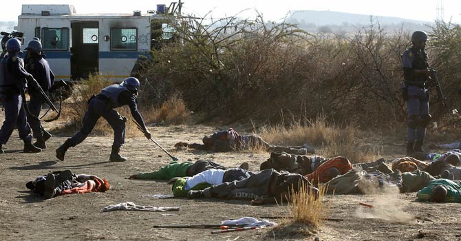 A policeman collects weapons that were supposedly used by protesting miners after they were shot outside a South African mine in Rustenburg, 100 km (62 miles) northwest of Johannesburg, August 16, 2012