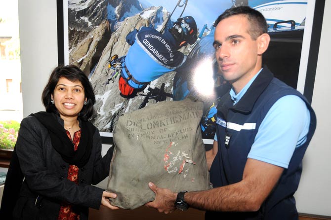 French High Mountain Gendarmerie Squad captain Emmanuel Vegas (R) gives to a representative of the Embassy of India in Paris, Satwant Khanala, a diplomatic bag belonging to the Indian Government after it was found at the Bossons Glacier, near the Mont Blanc in the French Alps — Photo by AFP