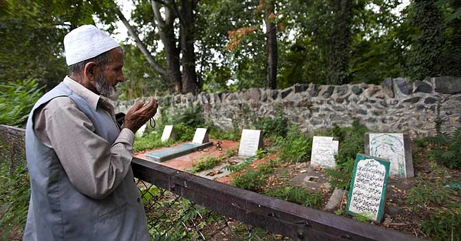 kashmir-unmarked-graves-ap- A Kashmiri man prays near an unmarked grave inside a martyrs graveyard in Srinagar, Kashmir. The Tombstone reads, "unidentified fifteen year old boy shot and killed by Border Security Force soldiers on 5th September 2003." - Photo by AP